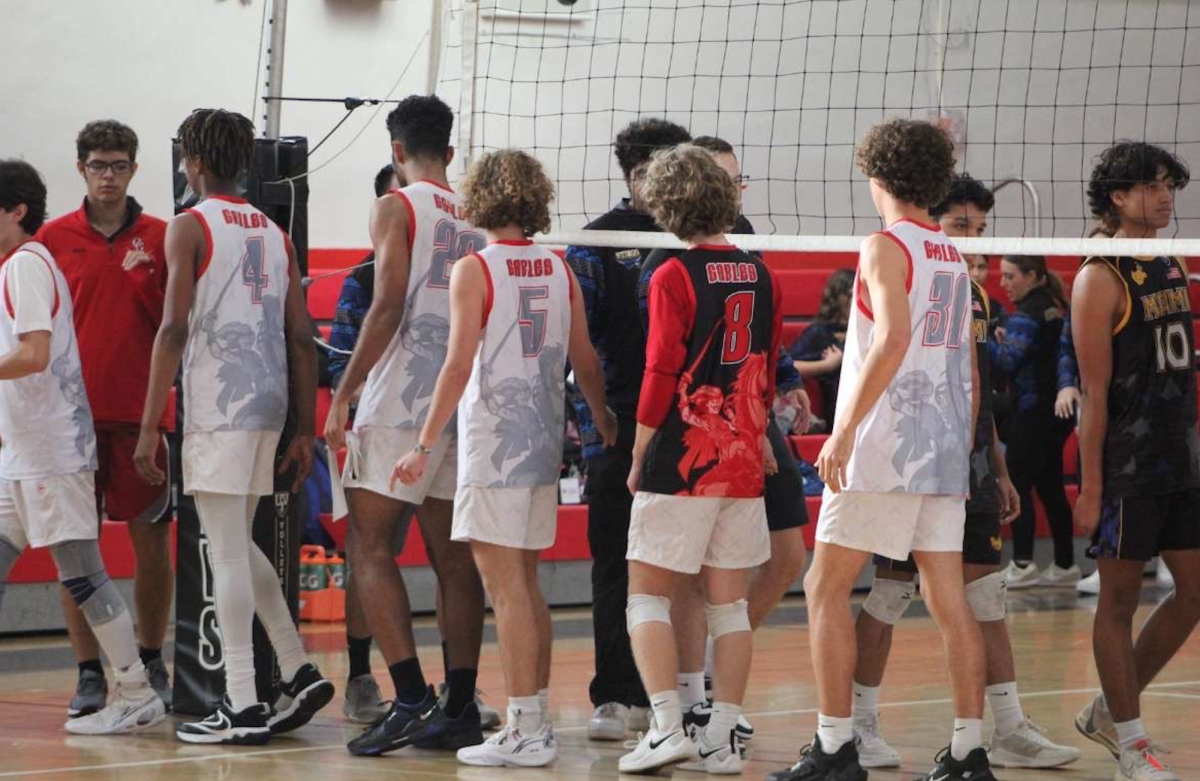 Commemorating the end of their game, the Varsity Boys Volleyball team and the Boys Varsity Miami High Volleyball team line up for their "handshake lines". 
